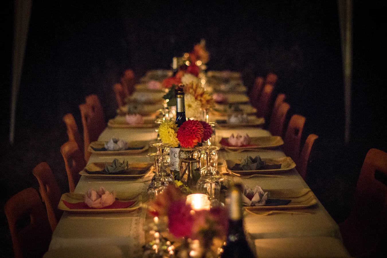 Elegant dinner table set with plates, glasses and bottles of wine.