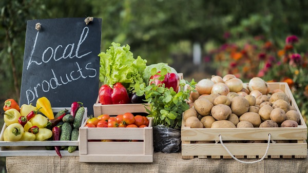 Counter with fresh vegetables and a sign of local products.