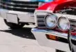 Bright classic cars line a street, with a red vintage car in front showing chrome headlights and a grille in sharp focus.