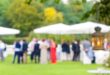 A close-up of a white lantern hanging from a tree with a blurry view of the wedding reception in the background.