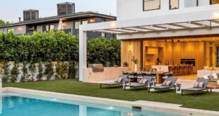 A modern white two-story home with a backyard swimming pool, raised spa, green lawn, and covered outdoor seating area.